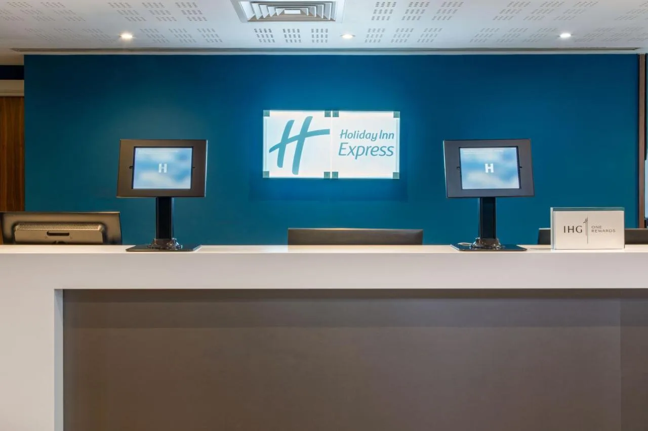 a counter with two monitors on a blue wall at Holiday Inn Express Birmingham - Snow Hill by IHG in Birmingham